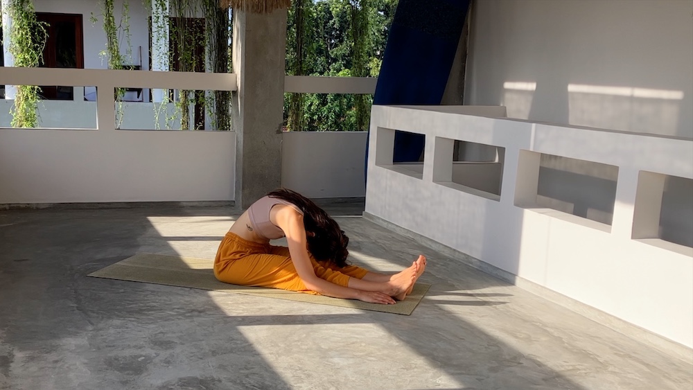 Junge Frau zeigt die Yogaposition "die Raupe"